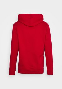 Sudadera roja con capucha y manga larga, hecha de un tejido suave y texturizado. Presenta un bolsillo tipo canguro y puños acanalados. Se muestra la vista posterior.