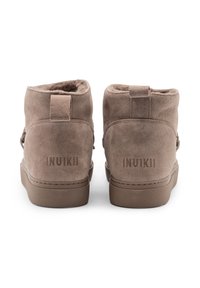 Brązowe zamszowe botki za kostkę z miękką podszewką, płaską gumową podeszwą i tłoczonym logo z tyłu, z uchwytem ułatwiającym zakładanie.