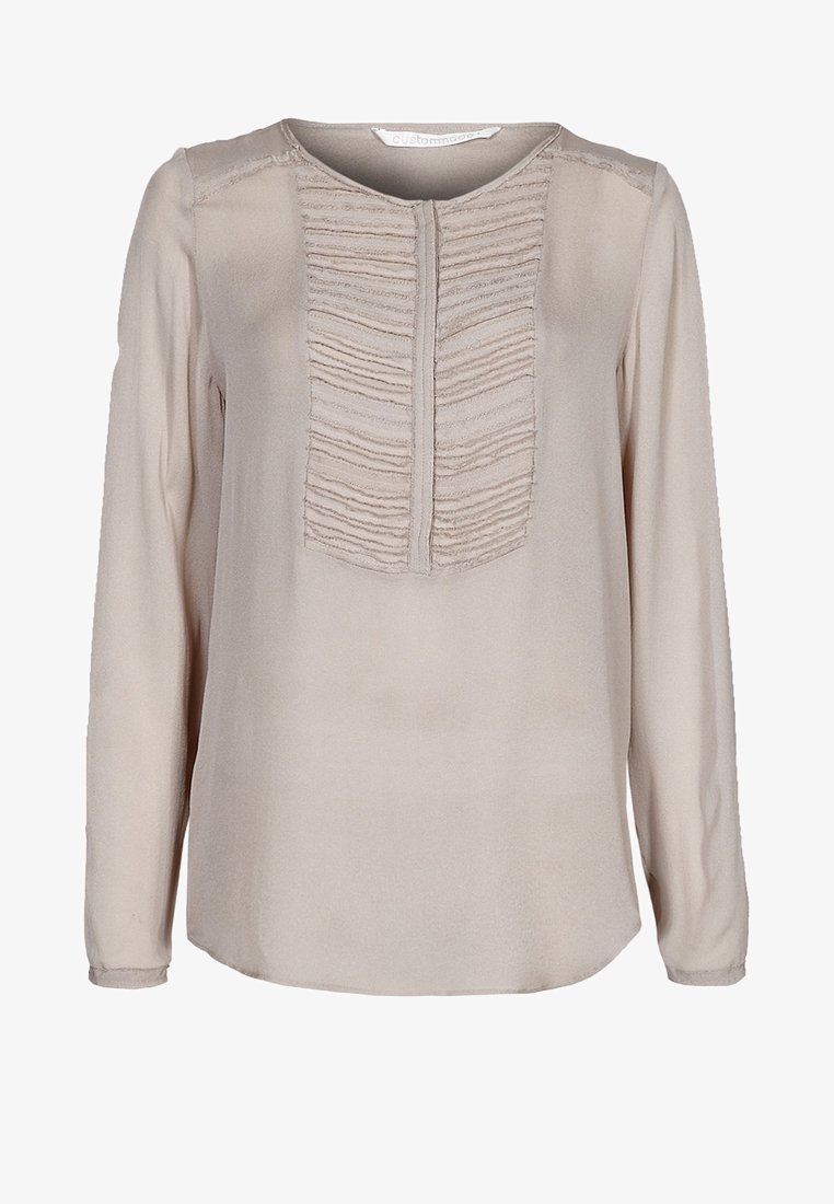 Blouse beige à manches longues avec un panneau volanté texturé au centre, encolure ronde et tissu doux et lisse. Ourlet incurvé.