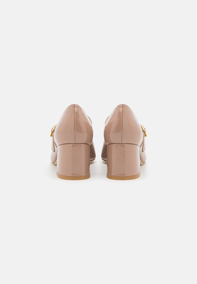 Chaussures à talons block en cuir verni nude avec un bout rond et un accent doré sur le côté. Texture lisse et finition brillante.