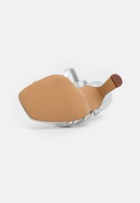 Srebrny but na wysokim obcasie z kwadratowym noskiem i teksturowaną podeszwą. Ozdobne paski krzyżują się na stopie, ukazując gładkie wykończenie ze skóry.