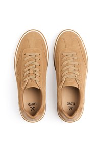 Beżowe zamszowe sneakersy z okrągłym noskiem, płaskimi sznurówkami, kontrastującą białą podeszwą oraz wykończeniem szewnym na cholewce. Widoczne logo marki wewnątrz.