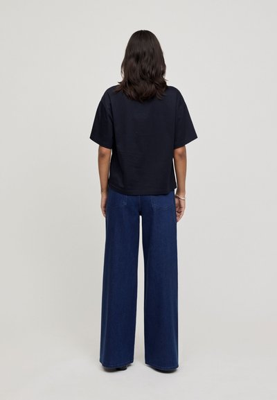 Navy cotton t-shirt with a boxy cut and short sleeves, paired with wide-legged dark denim jeans featuring back pockets and a simple design.