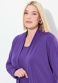 Lila, leichter Cardigan, der über einem passenden Oberteil getragen wird. Glattes Material, offenes Frontdesign und lange Ärmel. Schlichte, elegante Silhouette.