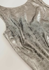 Silver metallic sleeveless dress with a smooth texture, slight sheen, and a relaxed fit. Features subtle wrinkling and clean edges.