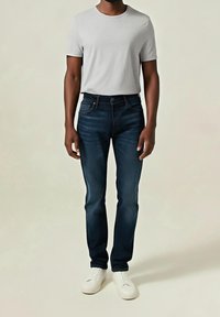 Camiseta gris de cuello redondo combinada con vaqueros de mezclilla azul oscuro, con un diseño clásico. Completado con zapatillas blancas con cordones, simples y versátiles.