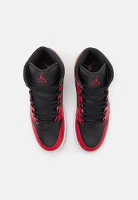 Sneakers alti con una struttura in pelle nera e dettagli in pelle verniciata rossa, punta perforata e lacci neri, con un logo prominente.