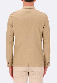 Giacca beige in tessuto texturizzato, con spacco singolo sul retro e polsini abbottonati. Finitura liscia con vestibilità su misura.