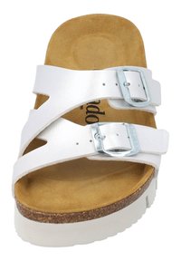 Sandale blanche à brides croisées avec boucles métalliques, semelle en liège et semelle en caoutchouc blanche. Tige en cuir lisse et doublure intérieure texturée.