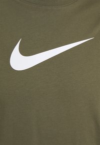 Olivově zelené bavlněné tričko s velkým bílým logem Nike swoosh na přední straně. Hladký povrch a klasický design s kulatým výstřihem.