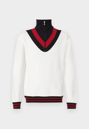 Pullover branco com gola alta, apresentando um design em V nas cores preto e vermelho na zona do pescoço. Punhos e barra canelados com riscas vermelhas e pretas.