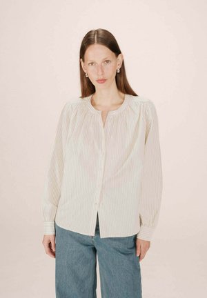 Chemise à rayures légères avec un col rond, des épaules froncées et des manches longues ; associée à un pantalon en denim bleu large.