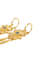 Gouden bloemenoorbellen hebben ingewikkelde bloemblaadjesdetails, een centrale blauwe edelsteen en een hangend ontwerp met gebogen haken voor een veilige bevestiging.