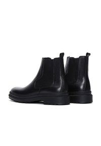 Bottines Chelsea en cuir noir avec des panneaux latéraux élastiques, des languettes de tirage et des semelles en caoutchouc épaisses, présentées de dos et de profil.