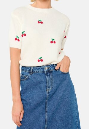 Suéter blanco de manga corta con motivos de cerezas rojas, combinado con una falda de mezclilla azul de talle alto. El suéter está tejido con una textura suave.