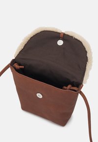 Bruine leren schoudertas met een zachte beige fleece bovenkant. Heeft een donkere stoffen binnenkant en een zilveren drukknoopsluiting om items veilig op te bergen.