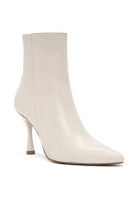 Botín de cuero beige con punta afilada y un tacón alto y delgado. Textura suave con diseño minimalista, sin herrajes ni patrones visibles.