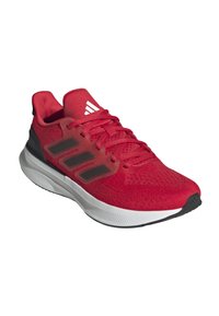Zapatilla deportiva roja con parte superior de malla texturizada, tres rayas negras, suela blanca redondeada y detalles de goma negra en la punta y el talón.