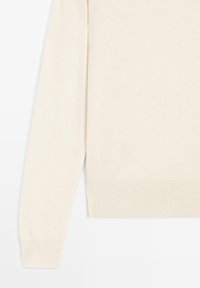 Kremfarvet strikket trøje med lange ærmer og ribstrikkede manchetter og kant, vist fra taljen og ned på en hvid baggrund.