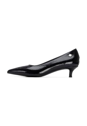 Zapato de tacón bajo de charol negro con punta afilada y un pequeño detalle plateado en el lateral. Textura suave y brillante.