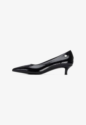 Zapato de tacón bajo de charol negro con punta afilada y un pequeño detalle plateado en el lateral. Textura suave y brillante.