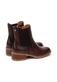 Bottes de cheville en cuir marron avec des panneaux élastiques sur les côtés, bout rond et talon empilé. Détail de zip doré et tige texturée. Couture renforcée.