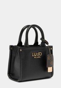 Sac à main en cuir noir avec une finition texturée, logo doré et quincaillerie dorée. Il dispose de poignées courtes et d'une étiquette brune avec un motif de logo.