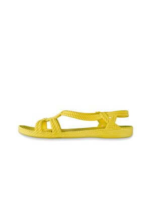 Gelbe Sandale mit einer strukturierten, gewebten Oberseite, offenen Zehen und verstellbaren Riemen. Flache Sohle mit gerippten Details für besseren Halt.