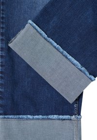 Jeansstoff in Dunkelblau- und Hellblautönen mit ausgefransten Kanten und markanter Farbblockierung. Durchgehende Köperstruktur sichtbar.