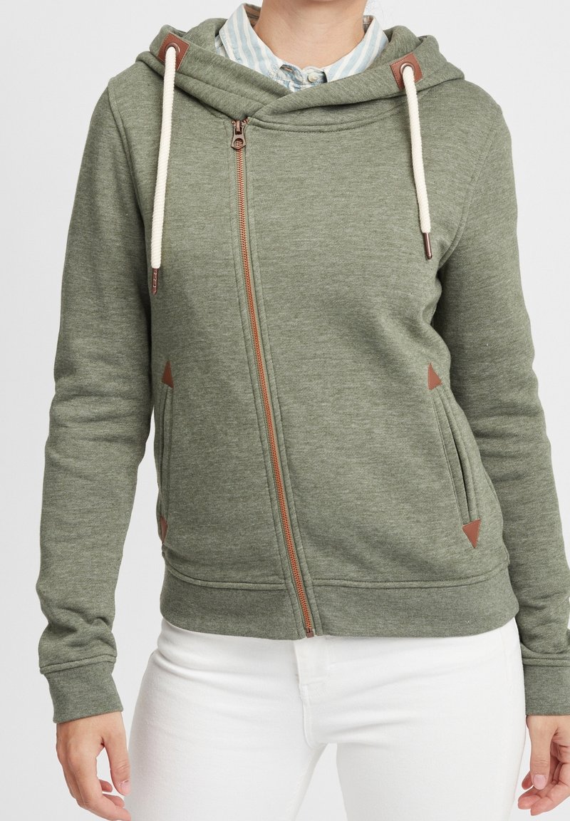 Sudadera de algodón verde con cremallera completa, cordones color crema, detalles marrones y bolsillos laterales, con un ajuste relajado y puños de canalé.