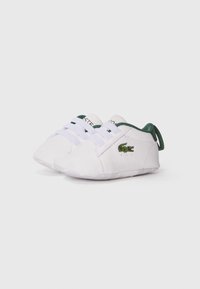 Sneakers bianchi con dettagli verdi, parte superiore in tessuto, design con lacci, piccolo logo di coccodrillo ricamato sul lato e suola morbida.