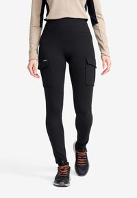 Svarta leggings med hög midja, med två stora cargofickor på sidorna. Slät textur, elastiskt tyg och tapered ben-design.