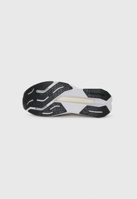 Semelle de chaussure avec des motifs de traction en caoutchouc noir, semelle intermédiaire texturée blanche et une forme élégante et allongée. Accents en gris clair.