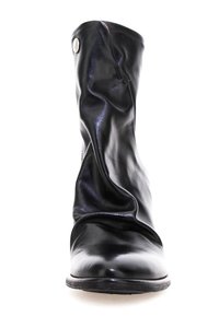 Bota de cuero negro con un diseño holgado, que presenta una textura suave, punta redondeada y un botón de acento plateado en el lateral.