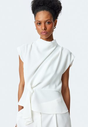 Top bianco senza maniche realizzato in tessuto morbido, con un collo alto e un design drappeggiato con un accento annodato in vita.