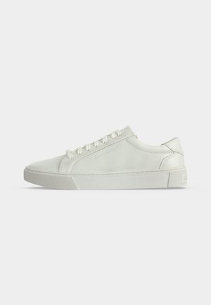 Weißer Low-Top Ledersneaker mit weißen Schnürsenkeln und einer strukturierten Gummisohle, seitlich vor einem einfarbigen Hintergrund gezeigt.