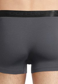 Boxer brevissimi grigi realizzati in tessuto elasticizzato con una superficie liscia. L'orlo nero presenta il nome del marchio in rilievo. Design minimalista.