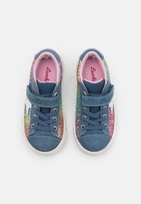 Blå semskede sneakers med et regnbue-glitrende design på siderne, lyserød inderside og justerbar rem over snørebåndene.
