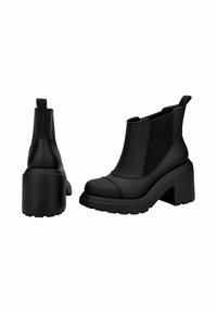 Bottines en cuir noir avec des panneaux élastiques sur les côtés, un talon épais, une semelle en caoutchouc texturée et des coutures décoratives sur les orteils.