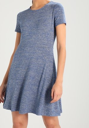 Nainen, jolla on päällään lyhythihainen, polvipituinen, meleerattu sininen A-linjainen mekko, jossa on vartalonmyötäinen vyötärö ja pyöreä pääntie.