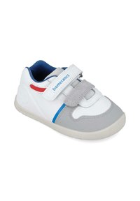 Zapatillas infantiles en blanco y gris con suela de goma texturizada, tira de Velcro, acentos azules y detalles rojos a lo largo de los lados.