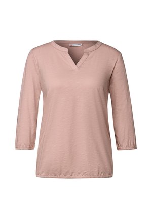 Haut à manches longues en rose clair avec un col en V et des poignets de manches froncés. Fabriqué en tissu doux et texturé pour le confort.