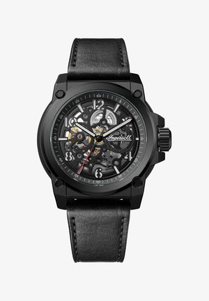 Sort automatisk ur med en gennemsigtig urskive, der viser komplekse gear, sølv- og guldaccenter samt et sort læderrem.