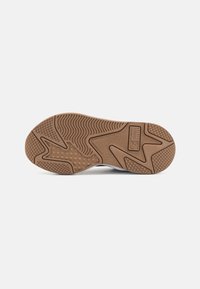 Semelle de chaussure avec une base en caoutchouc texturée, présentant des motifs en zigzag et en losange de couleur marron, avec un bord supérieur blanc faisant la transition vers la semelle.