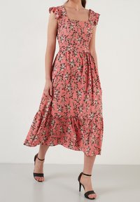 Vestido midi floral en rosa coral con mangas con volantes, escote cuadrado y dobladillo acampanado. Presenta patrones florales en negro, blanco y marrón.