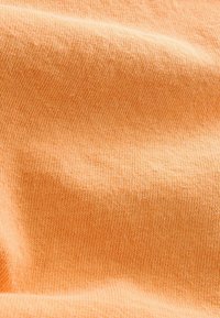 Gewebter Stoff in hellorange weist eine feine, glatte Textur auf und besitzt ein gleichmäßiges Muster aus engen Strickstichen.