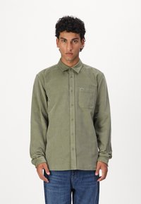 Groene corduroy overhemd met een button-down kraag, vo pocket en geborduurd logo. Lange mouwen en rechte zoom. G gedragen met blauwe jeans.