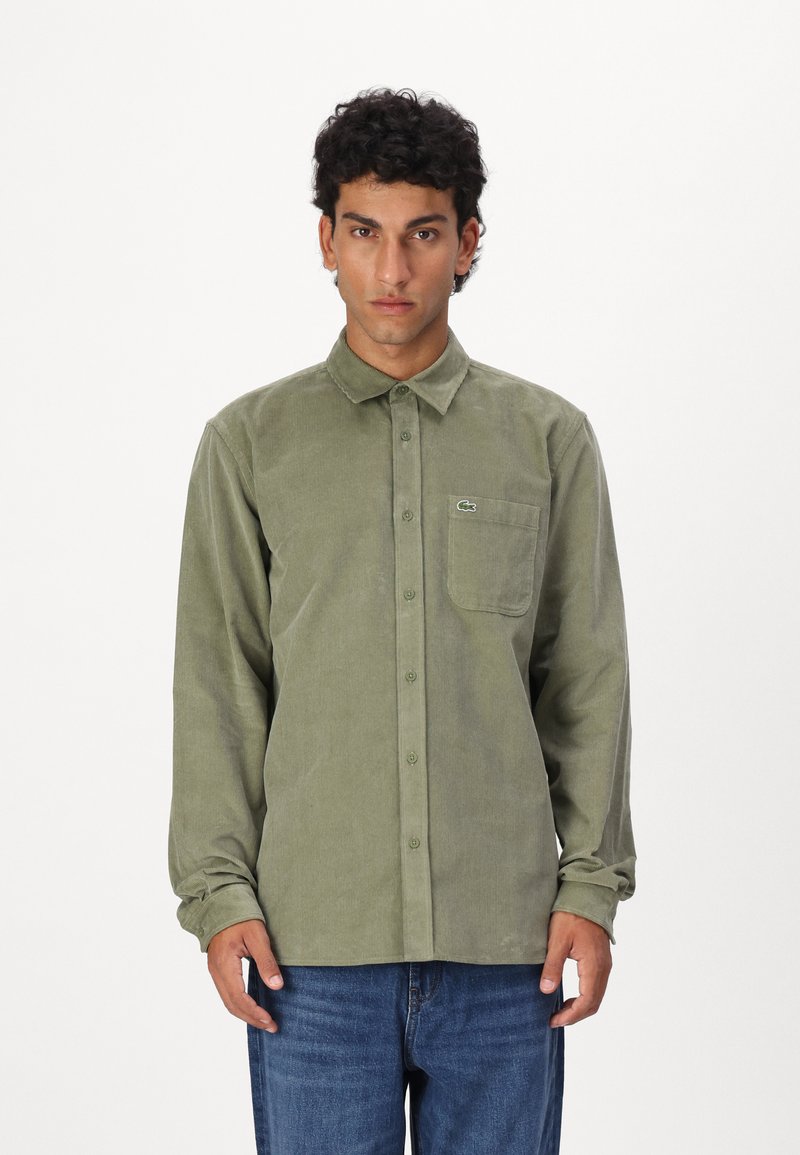 Groene corduroy overhemd met een button-down kraag, vo pocket en geborduurd logo. Lange mouwen en rechte zoom. G gedragen met blauwe jeans.