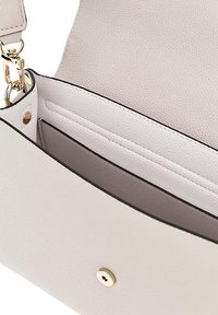 Interno di borsa in pelle beige chiaro, con chiusura a scatto dorata e tasche interne a fessura con fodera e bordi scuri a contrasto.