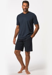 Camiseta de cuello en V a rayas navy combinada con pantalones cortos navy lisos. La camiseta tiene mangas cortas y un corte relajado; los pantalones cortos cuentan con bolsillos laterales.